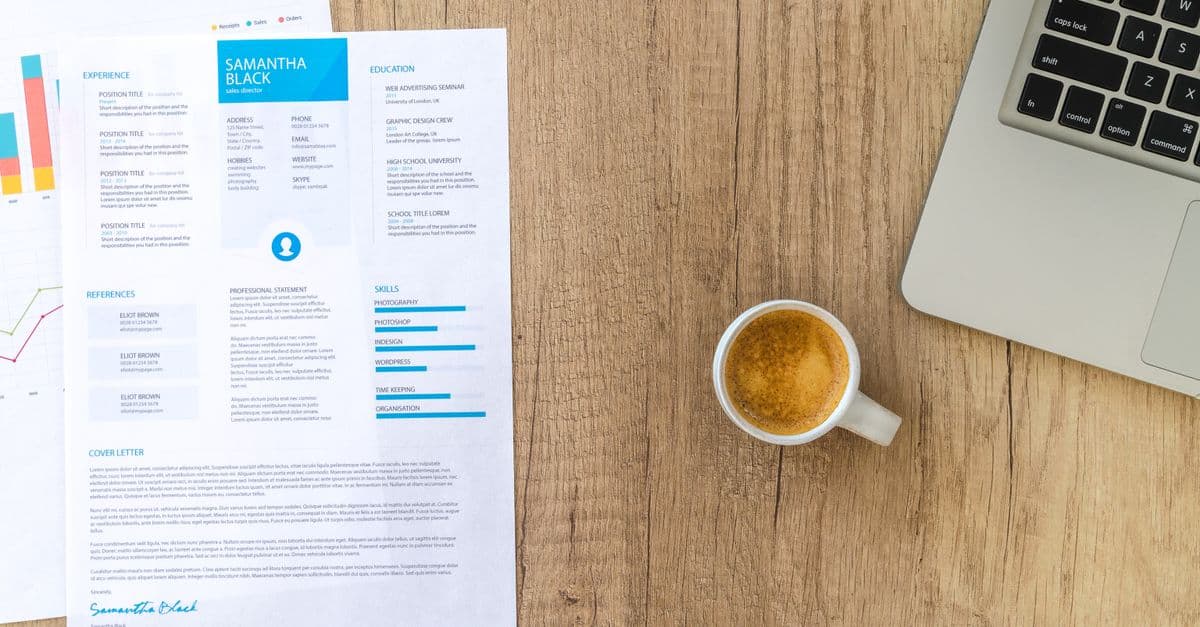 A printed resume with a skills section and a cover letter on a wooden desk, beside a cup of coffee and a laptop.